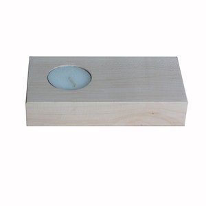 May include: A light wood candle holder with a round cutout for a tea light candle.