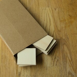 Puede incluir: Una pila de finas l&aacute;minas de madera de color marr&oacute;n claro sobresalen parcialmente de una caja de cart&oacute;n marr&oacute;n. Las l&aacute;minas de madera est&aacute;n dispuestas en forma de espiga.
