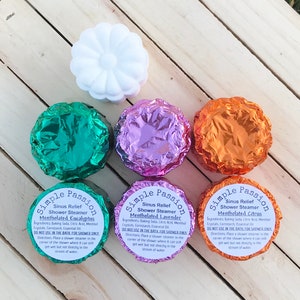 K&ouml;nnte beinhalten: Vier Duschdampfer in Folie verpackt, mit Etiketten mit der Aufschrift "Simple Passion Sinus Relief Shower Steamer Mentholated Eucalyptus", "Simple Passion Sinus Relief Shower Steamer Mentholated Lavender" und "Simple Passion Sinus Relief Shower Steamer Mentholated Citrus".