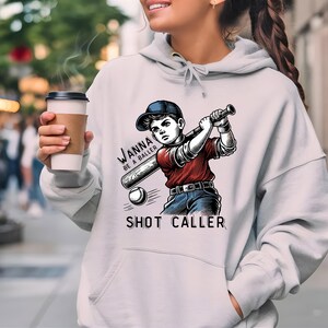 May include: A white hoodie with a baseball player graphic and the text "Wanna be a baller? Shot Caller".