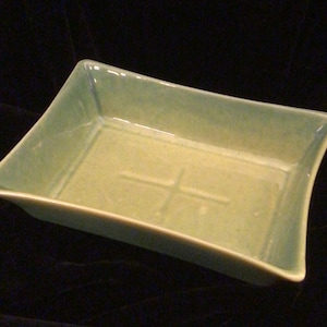 Peut inclure: Un plat rectangulaire en céramique vert clair avec un motif de croix en relief au centre.