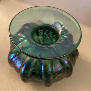 May include: A green iridescent glass vase with a wide, flared opening and a scalloped design. The vase has a speckled, multi-coloured pattern.