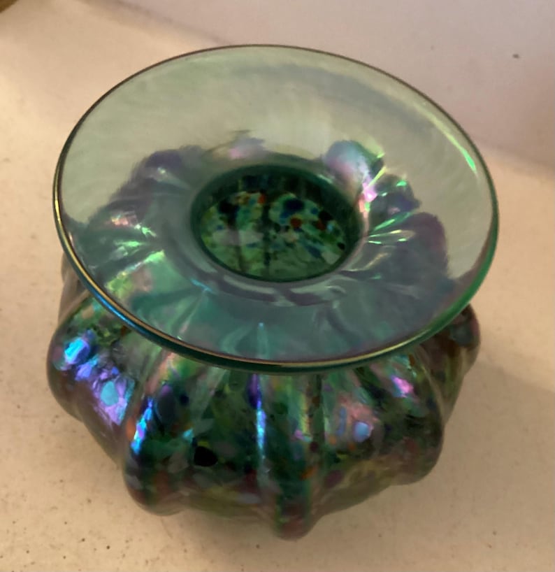 May include: A green iridescent glass vase with a wide, flared opening and a scalloped design. The vase has a speckled, multi-coloured pattern.