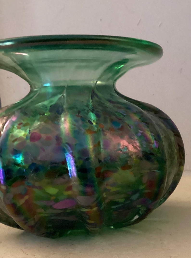 May include: A green glass vase with iridescent speckles and a rounded, bulbous shape.