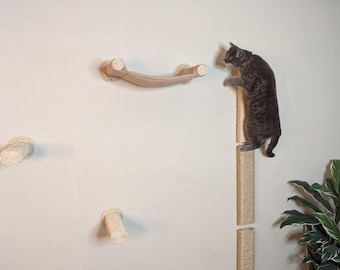 May include: A gray cat climbing a sisal-covered scratching post mounted on a white wall. The post is made of two sections, with a platform at the top. There are also three additional sisal-covered scratching posts mounted on the wall, as well as a sisal-covered cat bridge.