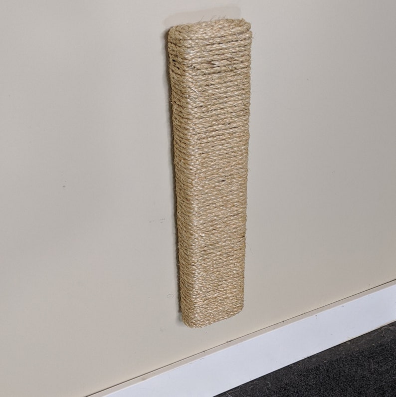 May include: A beige wall-mounted scratching post for cats, made of natural sisal rope.