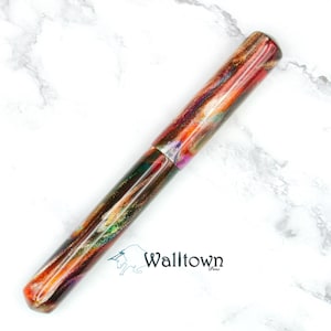 May include: A colourful pen with a marbled design in shades of red, orange, green, and purple. The pen has a rounded tip and a cap. The pen is lying on a white marble surface. The word "Walltown" is printed on the surface.