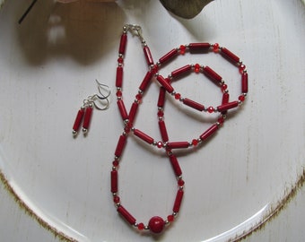 May include: A red coral necklace and earrings set with silver beads and a red coral pendant.