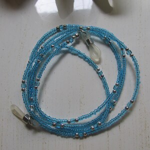 May include: A light blue beaded eyeglass chain with silver beads and clear plastic end pieces.