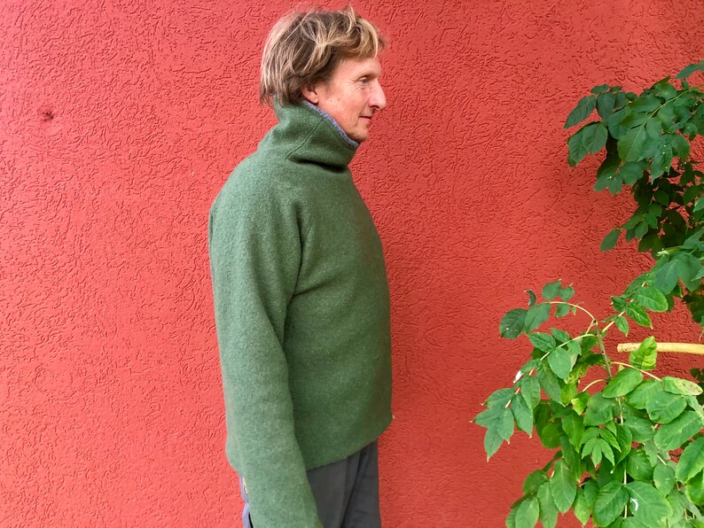 Puede incluir: Un su&eacute;ter verde de cuello alto con un cuello alto. El su&eacute;ter est&aacute; hecho de una tela suave y texturizada.