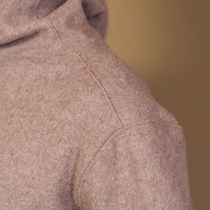 May include: Close-up of a brown turtleneck sweater with a seam running down the shoulder.