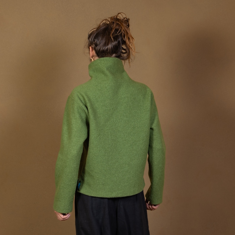 May include: A green mock neck sweater with long sleeves. The sweater is made of a soft, textured fabric.