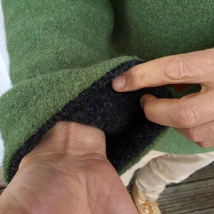 May include: Green sweater with a black fleece lining on the inside of the cuff. The sweater is made of a soft, fuzzy material.