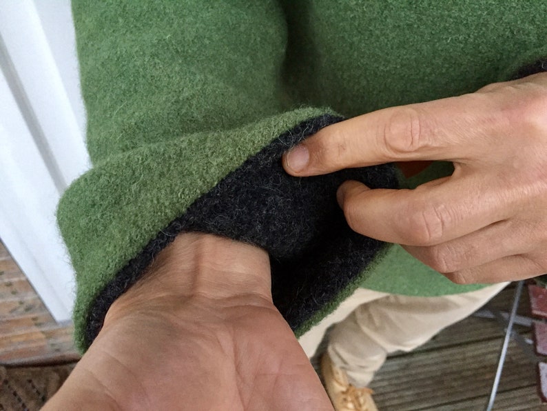 May include: Green sweater with a black fleece lining on the inside of the cuff. The sweater is made of a soft, fuzzy material.