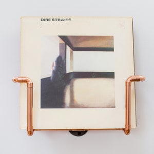 Vinyl record  holder that is wall mounted, ideal for holding up to 15 records. It is made from polished copper pipe, and allows you to flick through your records whilst still displaying the covers.