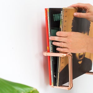 Vinyl record  holder that is wall mounted, ideal for holding up to 15 records. It is made from polished copper pipe, and allows you to flick through your records whilst still displaying the covers.