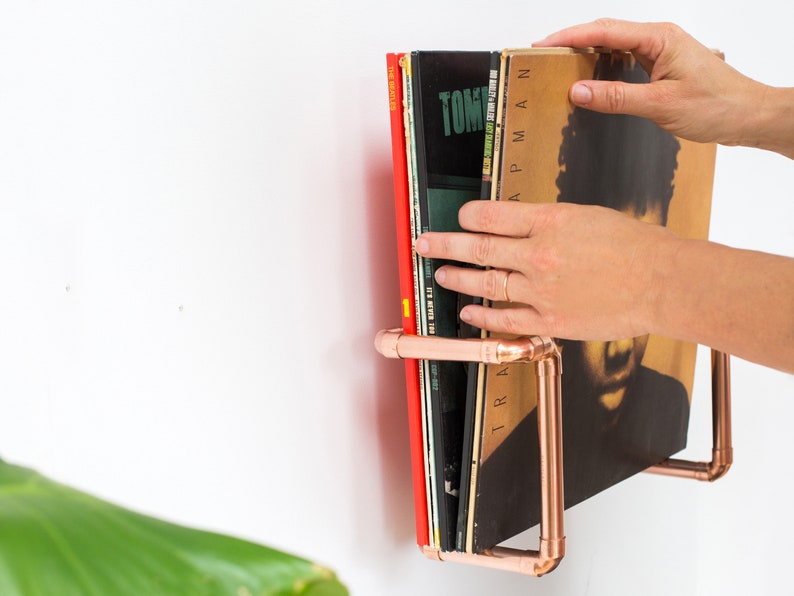 Vinyl record  holder that is wall mounted, ideal for holding up to 15 records. It is made from polished copper pipe, and allows you to flick through your records whilst still displaying the covers.