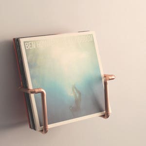 Vinyl record  holder that is wall mounted, ideal for holding up to 15 records. It is made from polished copper pipe, and allows you to flick through your records whilst still displaying the covers.