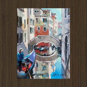 Peut inclure: Une peinture représentant une gondole sur un canal à Venise, en Italie. La gondole est bleue et un gondolier y est assis, vêtu d'une chemise à rayures bleues et blanches. Le canal est bordé de bâtiments et un pont se trouve en arrière-plan.