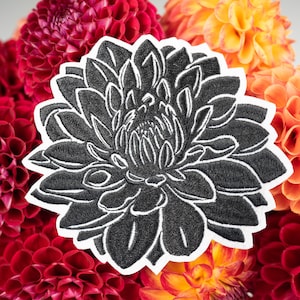 May include: Black embroidered flower patch with a white outline. The patch is surrounded by a variety of colorful flowers.