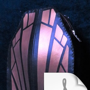 May include: A black leather clutch bag with a zipper closure. The bag has a geometric design with pink accents.