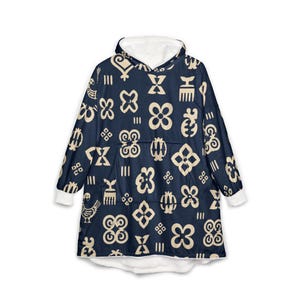 May include: A navy blue oversized hooded sweatshirt featuring a repeating pattern of cream-colored Adinkra symbols. The garment includes a large front pocket, long sleeves with white cuffs, and a white fleece-lined hood for added warmth and comfort.