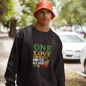 Pode incluir: Uma camisa de moletom preta com uma estampa gráfica de um sinal de paz e o texto "One Love Let's Get Together And Feel All Right".
