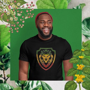 Könnte beinhalten: Ein schwarzes T-Shirt mit einem grünen, gelben und roten Löwen-Motiv in einem Schild. Der Löwe hat eine gelbe Mähne und eine rote Nase.