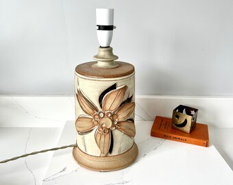 May include: A ceramic table lamp with a brown and white floral design. The lamp has a white shade and a brown cord.