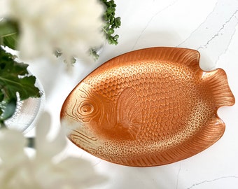 May include: A ceramic fish-shaped serving platter with a textured orange and white glaze.