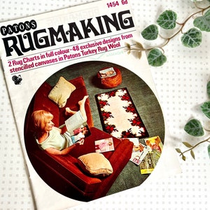 May include: A vintage magazine cover featuring a woman sitting on a sofa, reading a book. The cover is titled "Patons Rugmaking" and features a rug design with a floral pattern. The text on the cover reads "2 Rug Charts in full colour - 48 exclusive designs from stencilled canvases in Patons Turkey Rug Wool."