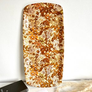May include: A rectangular serving tray with a floral pattern in shades of brown, orange, and white. The tray is made of a hard plastic material.