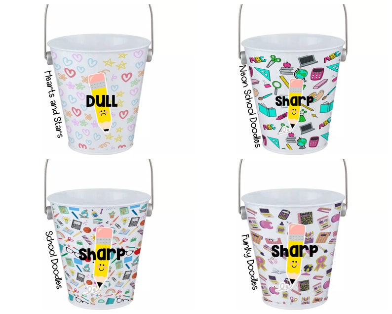 Puede incluir: Cuatro cubos de metal blanco con diferentes dise&ntilde;os. Cada cubo tiene un asa y presenta un l&aacute;piz con una cara y las palabras "Sharp" o "Dull". Los dise&ntilde;os incluyen corazones y estrellas, garabatos escolares, garabatos escolares de ne&oacute;n y garabatos funky.