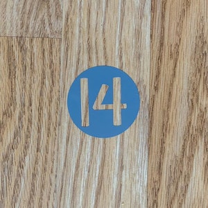 May include: A blue circle with the number 14 in white on a wooden surface.