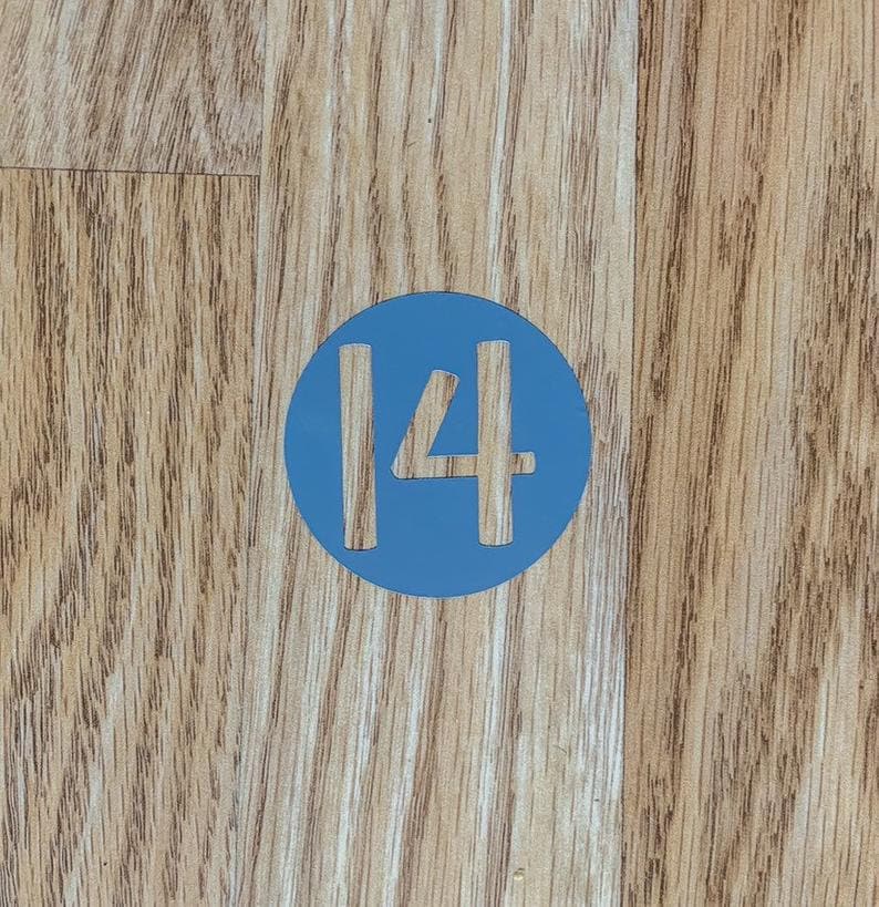 May include: A blue circle with the number 14 in white on a wooden surface.