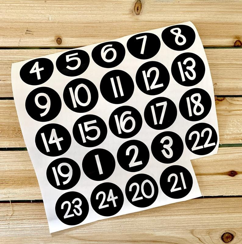 May include: A set of 24 black and white round stickers with numbers 1 through 24 printed in white on a black background.