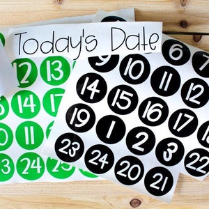 May include: Two sheets of stickers with black and green circles containing numbers from 1 to 25. The text "Today's Date" is printed on the top of the sheet with black circles.