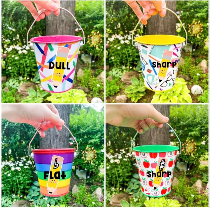 Puede incluir: Cuatro cubos met&aacute;licos peque&ntilde;os con diferentes dise&ntilde;os y colores. Cada cubo tiene un asa y un dise&ntilde;o de l&aacute;piz con una palabra que describe el l&aacute;piz: "Dull", "Sharp", "Flat" y "Sharp".