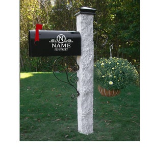 May include: Black mailbox with a white personalized label that says "N NAME 123 STREET". The mailbox is mounted on a white post with a black metal bracket.