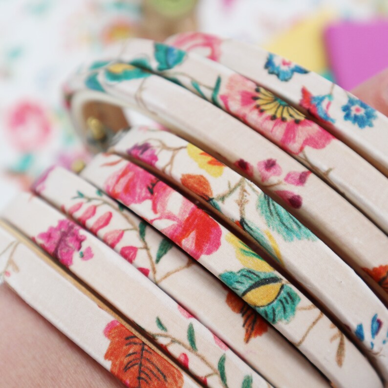 May include: A stack of white leather bracelets with a floral print in shades of pink, red, yellow, green, and blue.