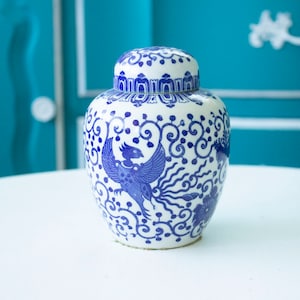May include: A white ceramic ginger jar with a blue phoenix design and matching lid. The jar features intricate blue patterns and a detailed bird motif, suitable for home decor.