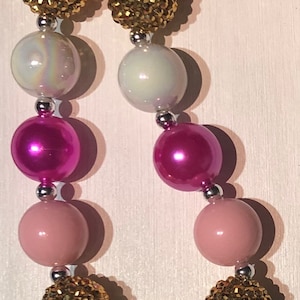 May include: A pink, white, and gold beaded necklace with a black and pink Minnie Mouse charm. The necklace is made with large, round beads and has a silver clasp.