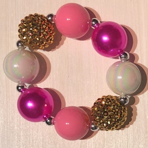 May include: A pink and gold beaded bracelet with iridescent white beads and silver spacers.