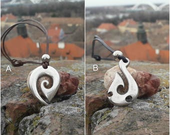 May include: Two silver pendants on brown leather cords. The pendant on the left is a spiral design. The pendant on the right is a hook design.