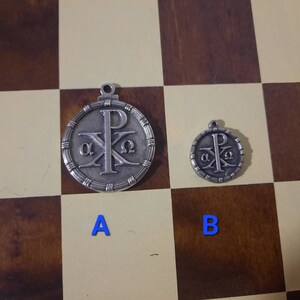 May include: Two silver pendants with a Christian symbol, the Chi Rho, and the Greek letters alpha and omega. The larger pendant is labeled "A" and the smaller pendant is labeled "B".