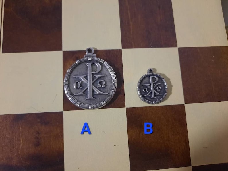 May include: Two silver pendants with a Christian symbol, the Chi Rho, and the Greek letters alpha and omega. The larger pendant is labeled "A" and the smaller pendant is labeled "B".