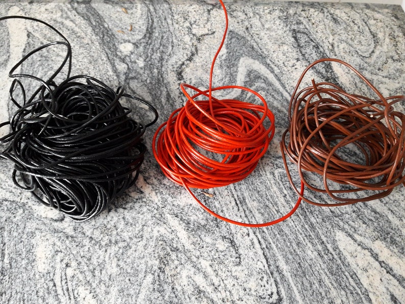 May include: Three spools of leather cord in black, red, and brown. The cords are coiled and ready for crafting projects.