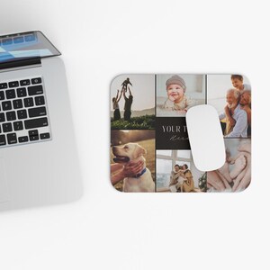 May include: A rectangular mousepad featuring a collage of family photos and a white computer mouse. The mousepad has a black background with the words "YOUR" and "Here" in a handwritten font. The photos include a baby, a dog, and a family.