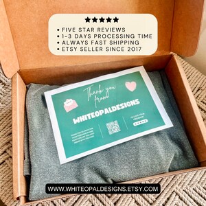 May include: A gray garment is neatly folded inside a cardboard box. A thank you card with a pink heart and the text "Thank you from WHITEOPALDESIGNS" is on top. The box also displays "FIVE STAR REVIEWS" and "ETSY SELLER SINCE 2017".