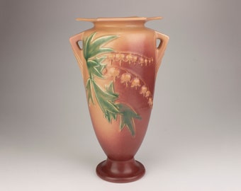 May include: A brown and green glazed ceramic vase with a floral design. The vase has two handles and a wide mouth.